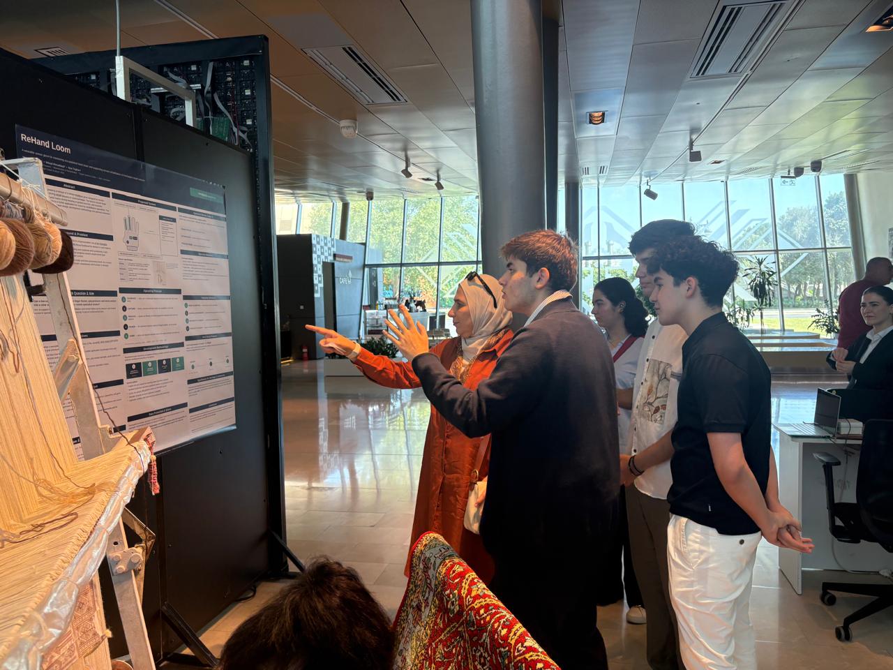 A visitor at the Azerbaijan National Carpet Museum discussing the ReHand Loom research poster with the project team